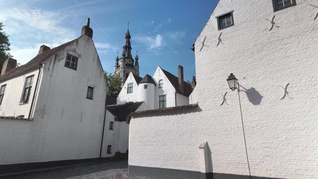 UNESCO beguinage Kortrijk Belgium tiltup view of historic white houses and church tower under blue sky