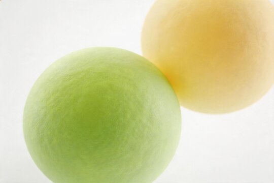 Two spherical fruits on white background