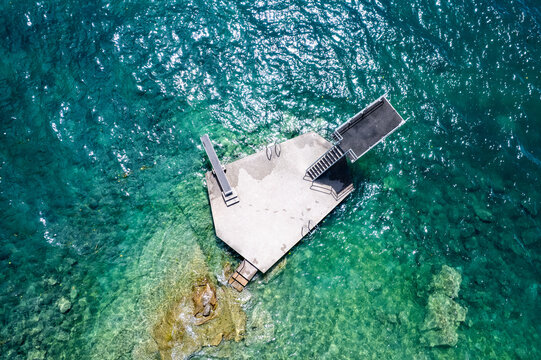 Aerial view of a concrete diving platform with stairs and diving board in the turquoise water of Lake Geneva Lutry, Vaud, Switzerland.