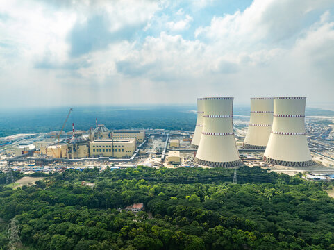 Aerial view of the Rooppur Nuclear Power Plant featuring massive cooling towers and industrial buildings surrounded by lush green forests in Pakuria, Rajshahi Division, Bangladesh.