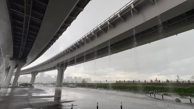 Rain pours from the gutters of the road bridge.