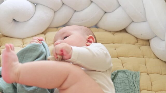 Cute baby boy learning to roll over from back to tummy on a soft bed. Sweet infant development milestone, active moving in nursery room. Early childhood, growth and parenting concept.