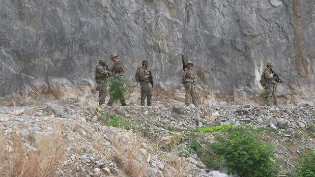 Soldiers conduct training exercise in rocky terrain during daytime