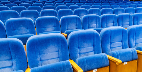 Naklejka premium Rows of empty blue velvet seat in theater. Concept of social distancing and waiting for event start.