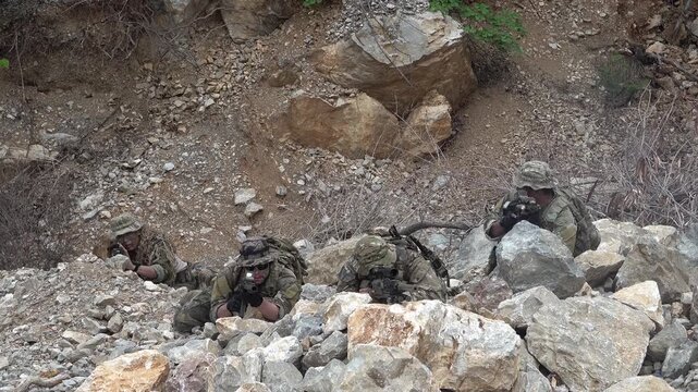 Soldiers engaged in tactical training exercise on rocky terrain