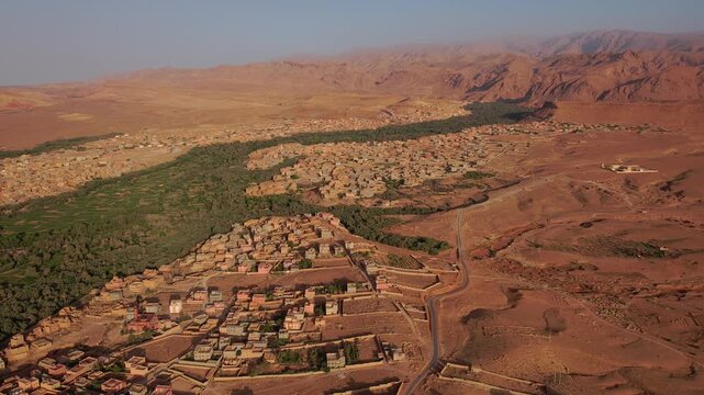Tinghir in Draa-Tafilalet, Morocco, between the High Atlas and Jbel Saghro ranges, showing Phoenix dactylifera oasis corridors, ksar districts and expanding desert settlement patterns, forward yaw