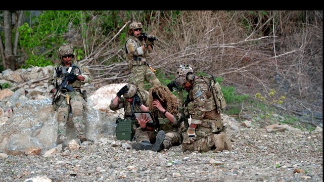 Military training operation on rocky terrain near a forest in broad daylight