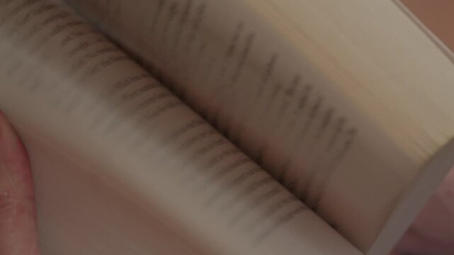 Person flipping through book pages in soft indoor lighting