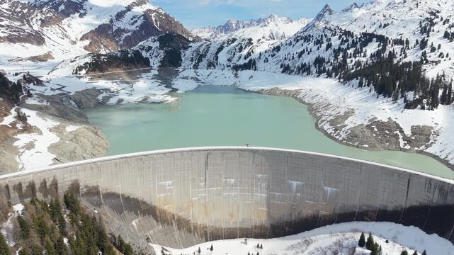 Aerial Flyby Hydroelectric Dam Reservoir Lake in Snowy Alpine Mountain