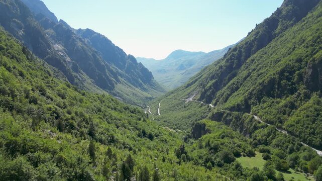 Aerial view of Theth Valley in the Albanian Alps, featuring lush forests, winding mountain roads, and dramatic peaks. Showcases the natural beauty of one of Albania&rsquo;s most popular travel destinations.