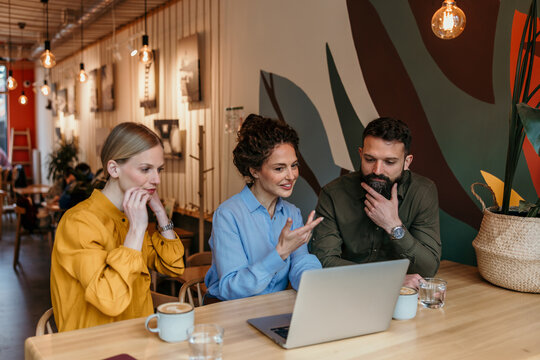 Business people collaborating with laptop at coffee shop