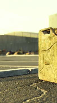 A container is placed on the asphalt near a road with buildings in the background under evening light. The setting suggests a quiet urban area likely at dusk time.