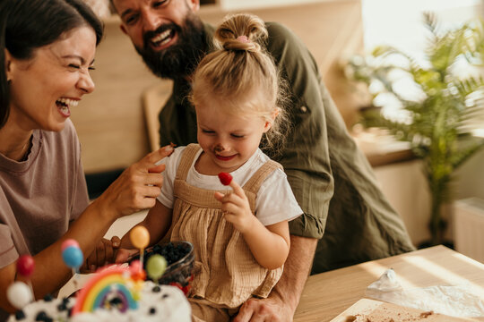 Family celebrating child's birthday by decorating cake