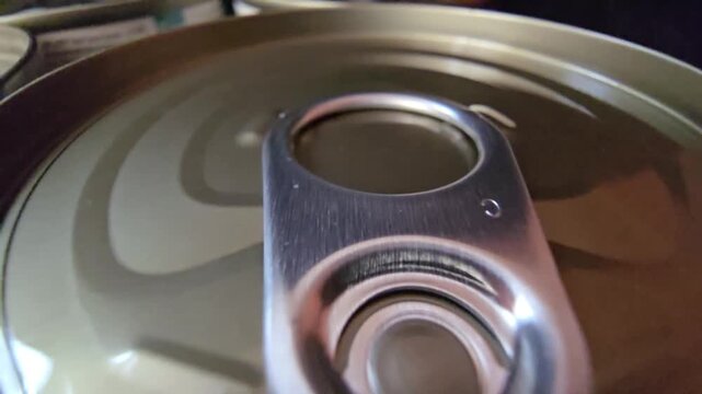 Macro shot of a metal tin can lid with an easy-open ring pull, highlighting food packaging and emergency storage.