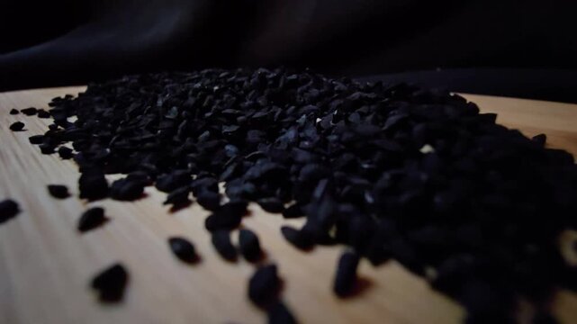 Macro shot of black seed, also known as nigella sativa or kalonji, spilling from a wooden bowl, perfect for herbal medicine and healthy food concepts.