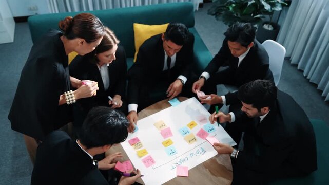 Top view of business people making scrum task board to manage workflow in workplace. Diverse marketing team drawing a line and use colorful stick notes to work on kanban. Creative office. Directorate.