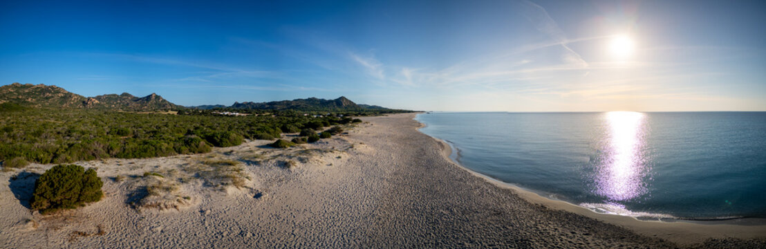 Aerial view of Berchida beach with white sand, turquoise sea, green Mediterranean scrub, and distant mountains under a clear blue sky Siniscola, Sardegna, Italy.