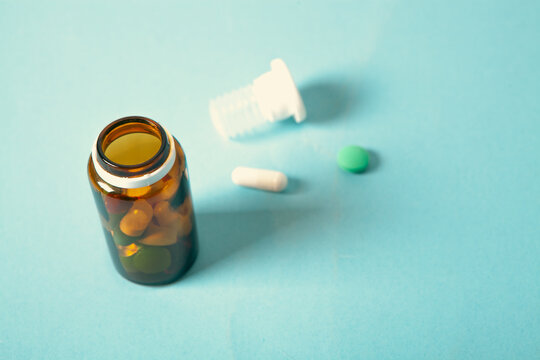 Pills and capsules on blue background. Focus on foreground, soft bokeh.