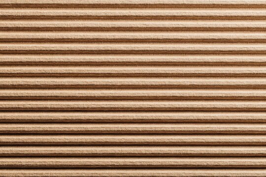 Detailed texture of corrugated cardboard with distinct parallel grooves and a natural brown hue