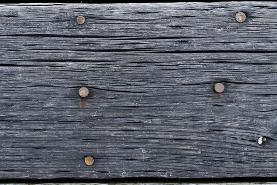 Dark weathered wooden plank with rusty iron nails