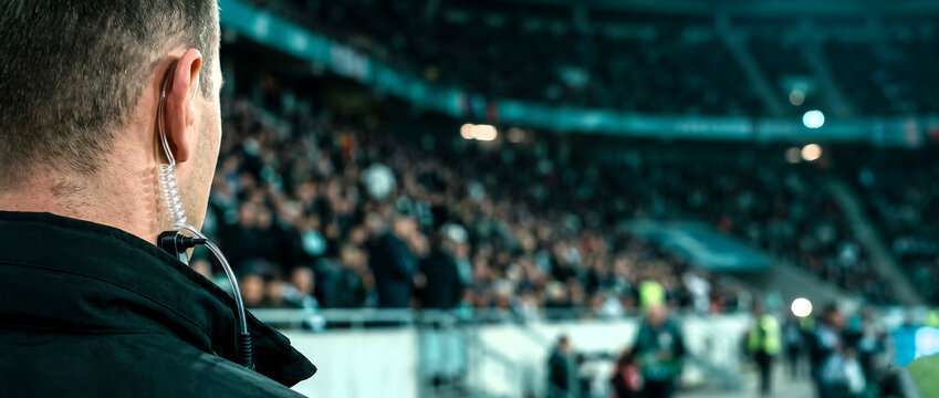 Security Guard Watching Crowd at Sports Stadium During Night Event