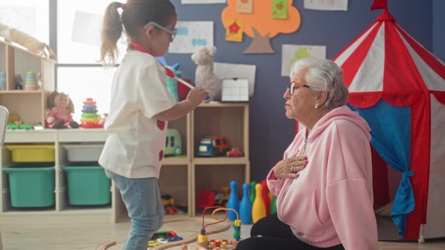 Woman with stethoscope listens to child's chest as girl leans in and her hand rests on chest in children's playroom; gentle affection.