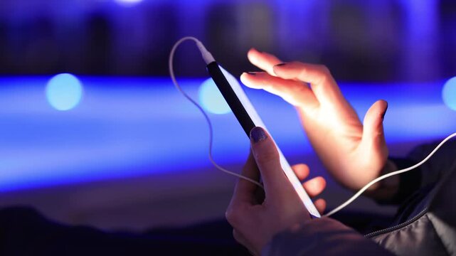 Woman using smartphone by pool at night &ndash; glowing screen, copy space, modern lifestyle.