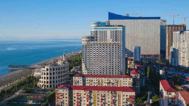 Static urban timelapse capturing the dramatic transition from daylight afternoon to twilight and dark night over Batumi city coast, showcasing modern illuminated skyscrapers and luxury hotels