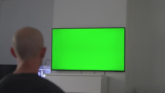Man watching green screen tv in modern living room