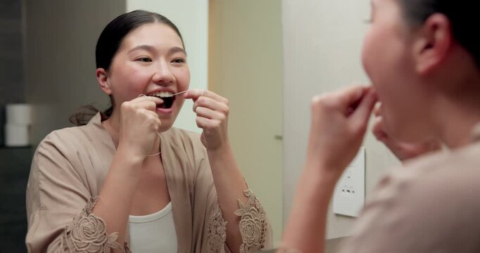 Mirror, cleaning and asian woman with dental floss in home for oral or gum care in bathroom. Female person, string or morning routine with reflection or cavity for bacteria or germ removal in house