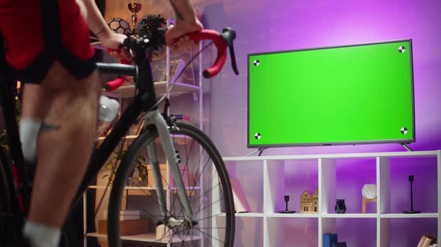 Man Cycling at Home with Green Screen TV Indoor Fitness and Chroma Key Mockup