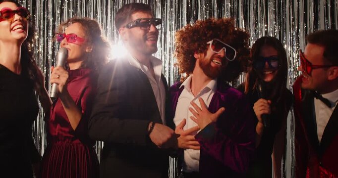 Cheerful group of friends singing karaoke using a microphone and dancing to music in a nightclub. Celebrate together, enjoying entertainment, fun, and happy moments in a festive and energetic party.