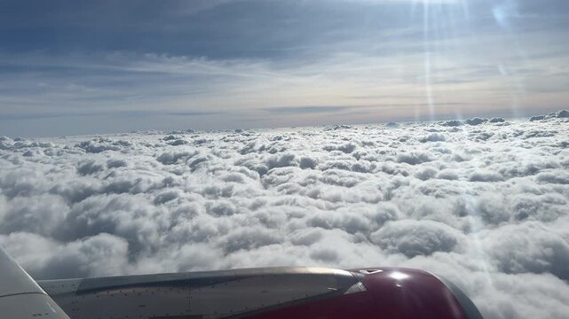 An airplane wing glides above a thick layer of clouds with sunlight streaming down. Ideal for travel content or aviation-themed projects.