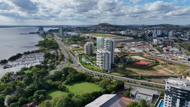 Lateral pan left to right across Porto Alegre's Zona Sul waterfront, showing the Gua&iacute;ba riverfront road, marina, and city skyline.