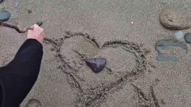 Heart sand beach drawing a romantic symbol in the sand being washed away by ocean waves