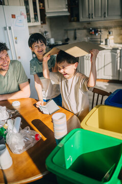 Father and children sorting waste for recycling in the kitchen