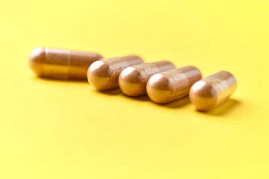 Ashwagandha (Withania somnifera) capsules. Concept for a healthy dietary supplementation. Bright paper background. Soft focus. Close up. Copy space