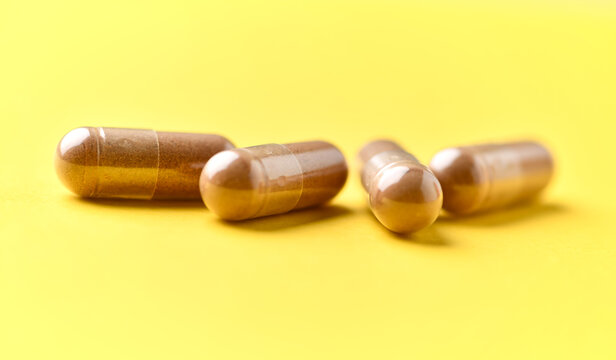 Ashwagandha (Withania somnifera) capsules. Concept for a healthy dietary supplementation. Bright paper background. Soft focus. Close up. Copy space.