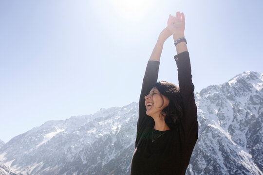 Smiling tourist reaching upward on snowy mountain