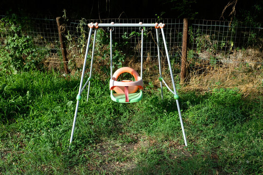 Empty plastic baby swing in a green meadow in Liguria Italy