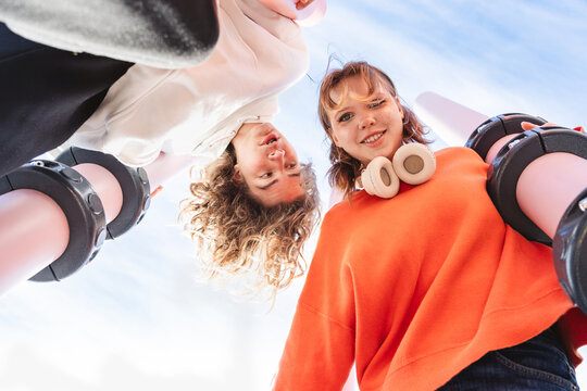 Friends looking down at camera against blue sky in summer