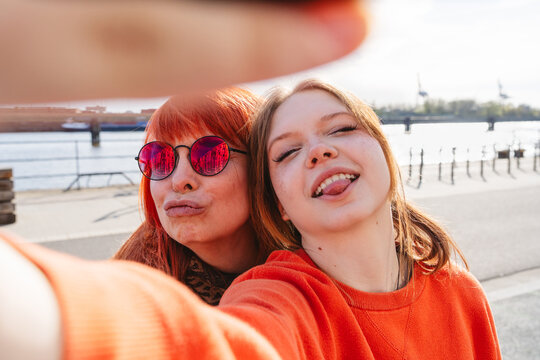 Mother and daughter taking a playful outdoor selfie by the river