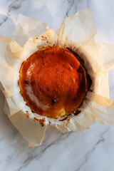 Fototapeta premium Whole homemade Basque burnt cheesecake in baking parchment paper.