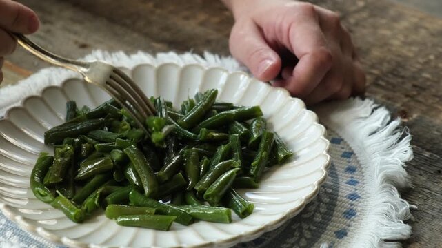 Person eating cooked green beans. Healthy vegetarian plant based meal
