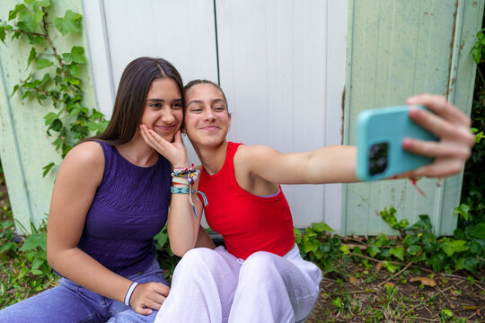 Friends sitting outdoors in the garden taking a selfie and smiling