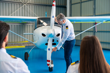 Pilot instructor explaining airplane propeller to students in hangar © unai