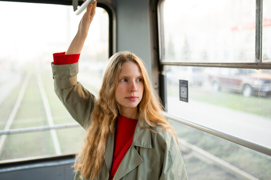 Commuter standing in a tram holding the handrail during a journey