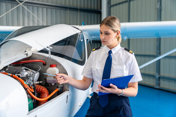 Female pilot checking small airplane engine during pre flight inspection © unai