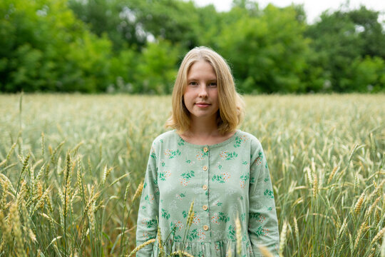 Portrait of woman in a summer wheat field wearing a green vintage dress