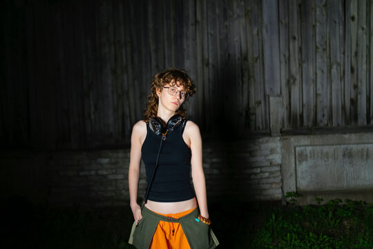 Young woman standing outdoors in the evening with headphone